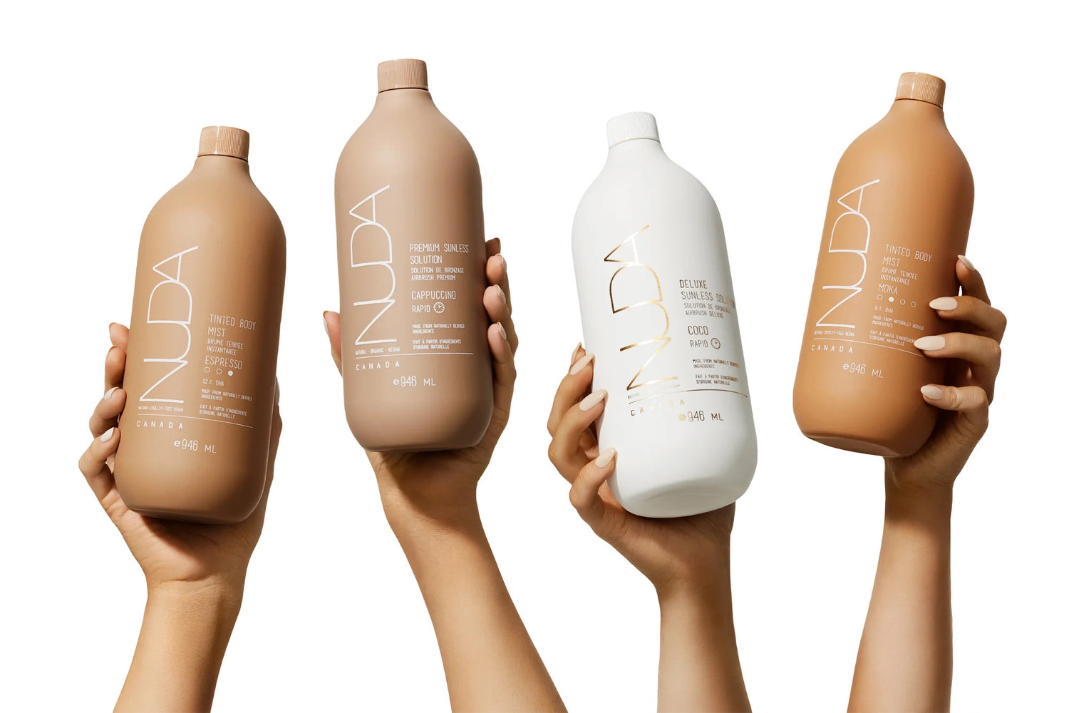 Four individual hands hold up a variety of sunless tanning bottles that hold products that will result in various hues.