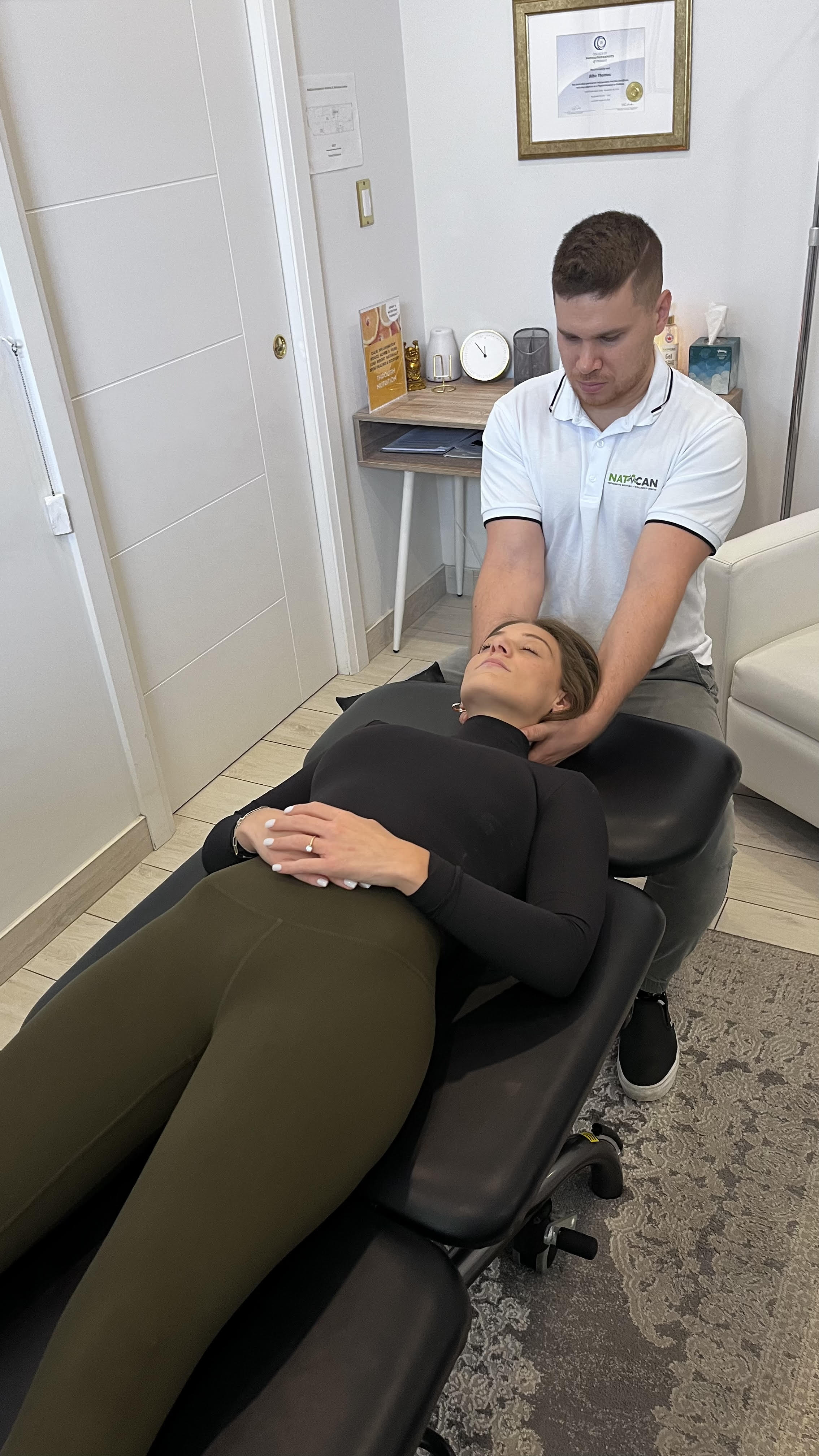 A woman in olive-coloured pants and a black shirt lays on her back on a treatment table to allow a health care professional assist her with sinus problems and headaches.